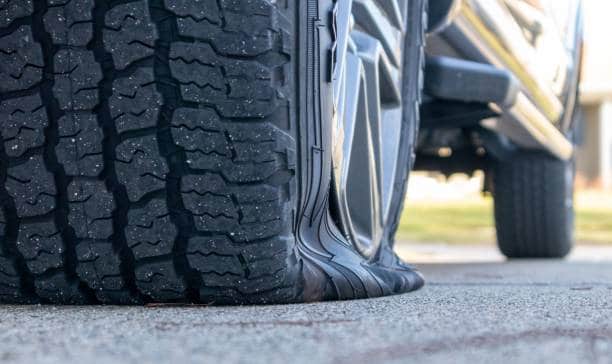 low angle view of a trucks flat tire on cement - SMC Towing Group Can You Drive With a Flat Tire? Proper Guide by SMC Towing Group
